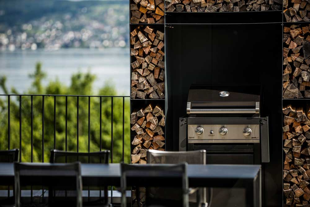 Grill auf Terrasse mit Holzstaufach